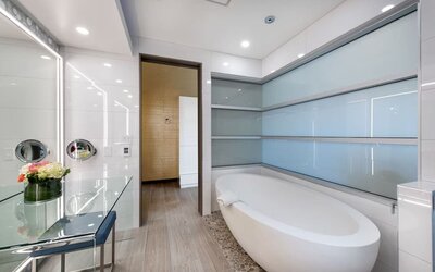 Contemporary bathroom with freestanding soaking tub, pebble flooring, and frosted glass wall panels at Shade Hotel Manhattan Beach.