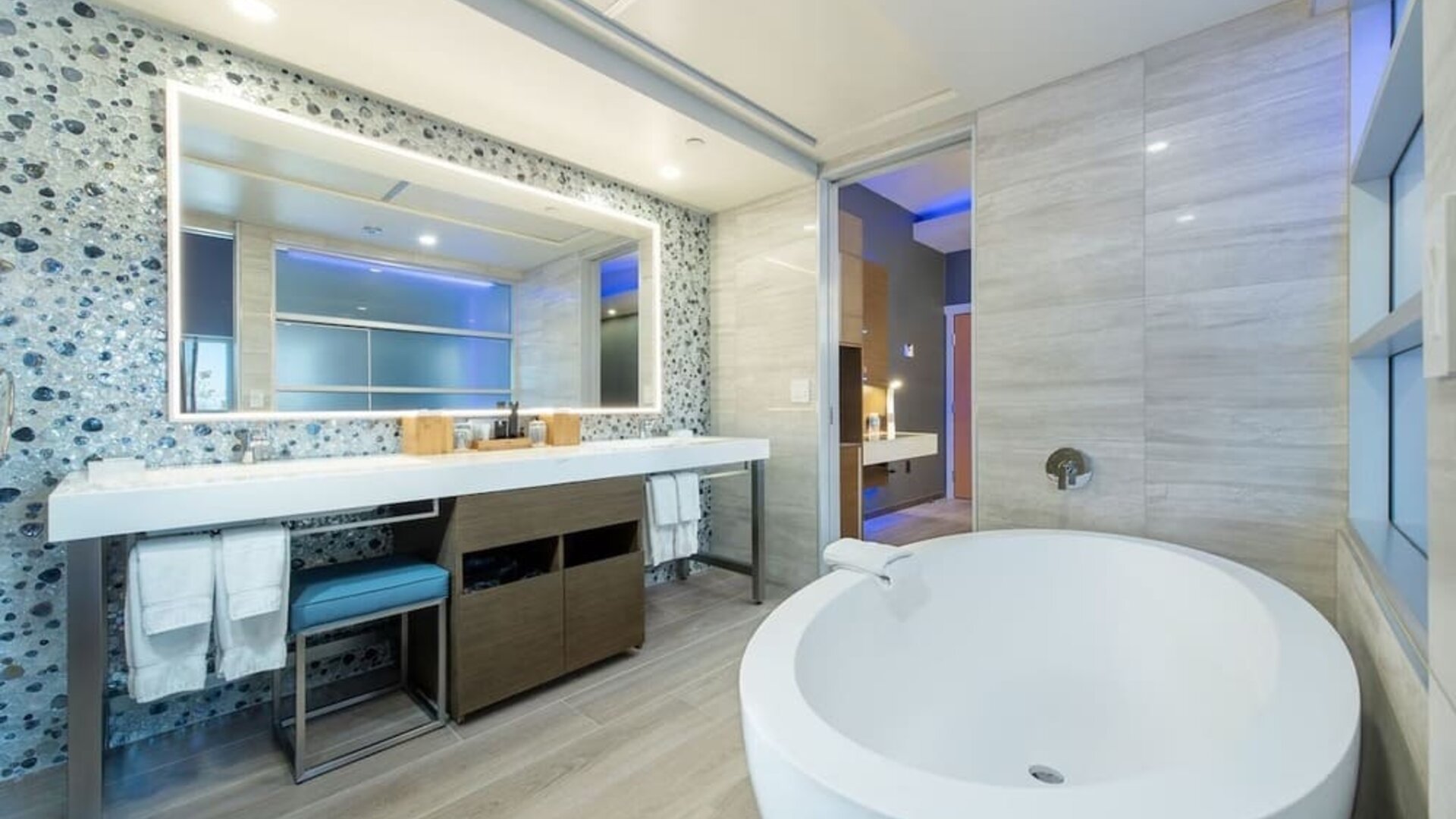 Spacious bathroom with freestanding tub, large vanity mirror, and mosaic accent wall at Shade Hotel Manhattan Beach.