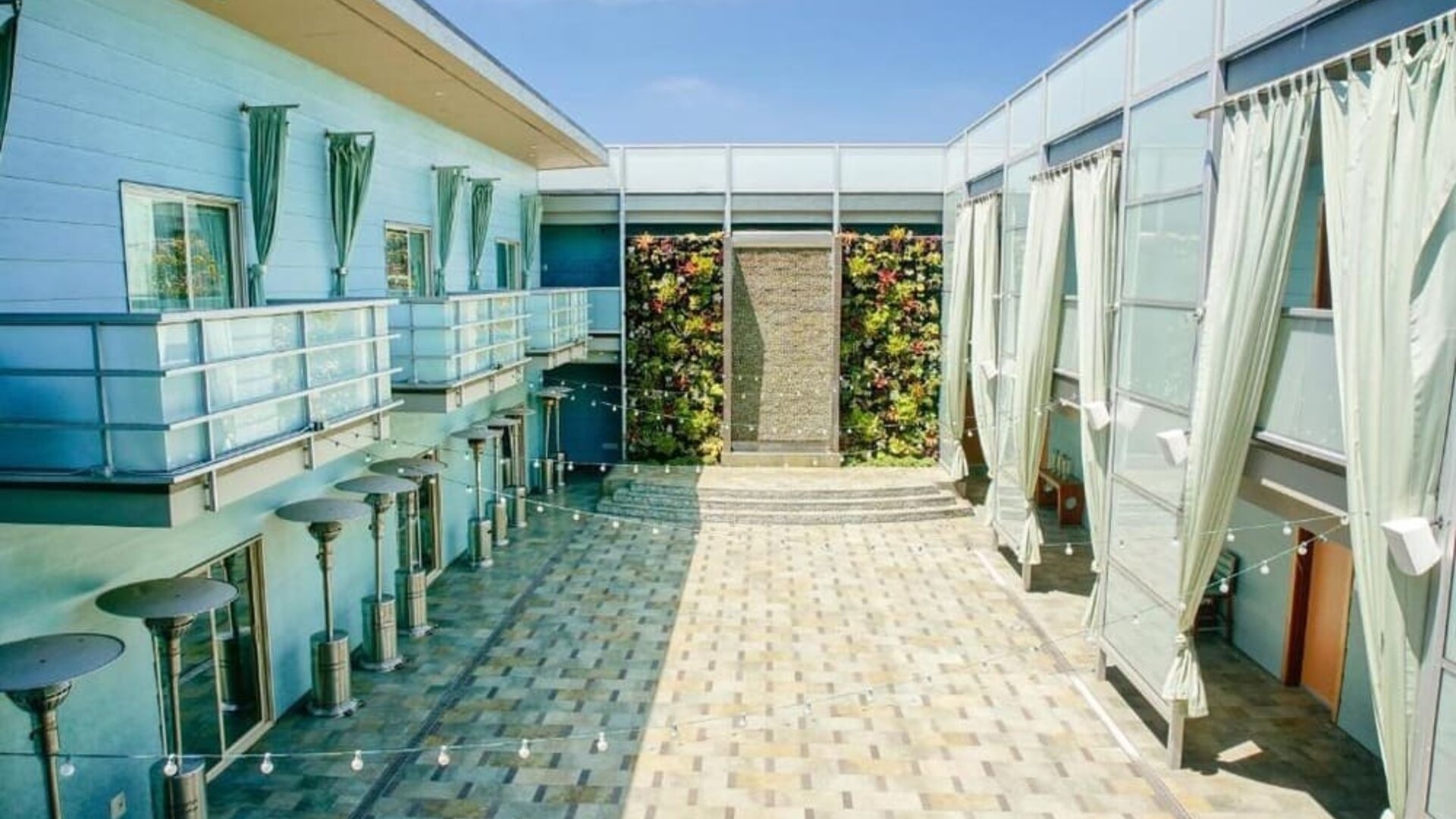 Open-air courtyard with tiled walkways, lounge areas, and vertical garden wall at Shade Hotel Manhattan Beach.