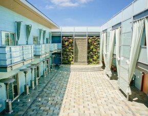 Open-air courtyard with tiled walkways, lounge areas, and vertical garden wall at Shade Hotel Manhattan Beach.