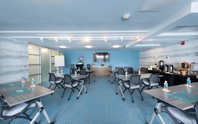 Meeting room with grouped tables, office chairs, presentation screen, and refreshment station at Shade Hotel Manhattan Beach.