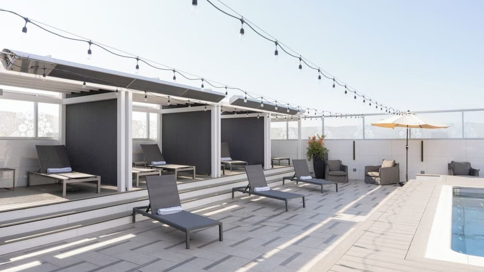 Rooftop pool deck with shaded cabanas, lounge chairs, and string lighting at Shade Hotel Manhattan Beach.