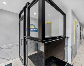 Modern reception desk area with marble-style flooring and bright yellow door frames at Days Inn Chinatown NYC.
