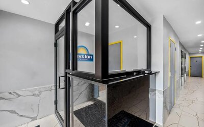 Modern reception desk area with marble-style flooring and bright yellow door frames at Days Inn Chinatown NYC.