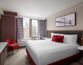 Spacious king guest room with red accents at Hilton Garden Inn New York/West 35th Street.