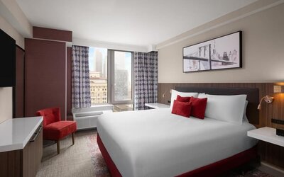 Spacious king guest room with red accents at Hilton Garden Inn New York/West 35th Street.
