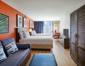 Spacious studio-style guest room with two beds and seating area at Courtyard Waikiki Beach.