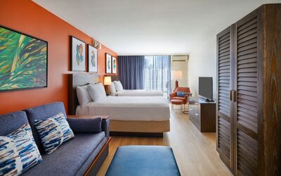 Spacious studio-style guest room with two beds and seating area at Courtyard Waikiki Beach.