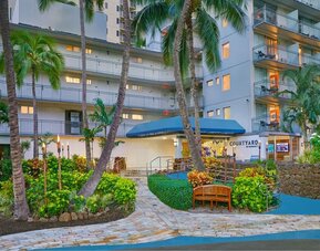 Tropical exterior entrance surrounded by palm trees at Courtyard Waikiki Beach.