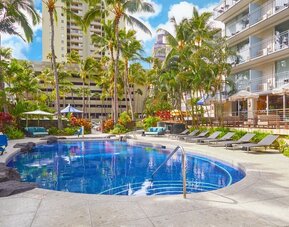 Outdoor swimming pool surrounded by palm trees at Courtyard Waikiki Beach.