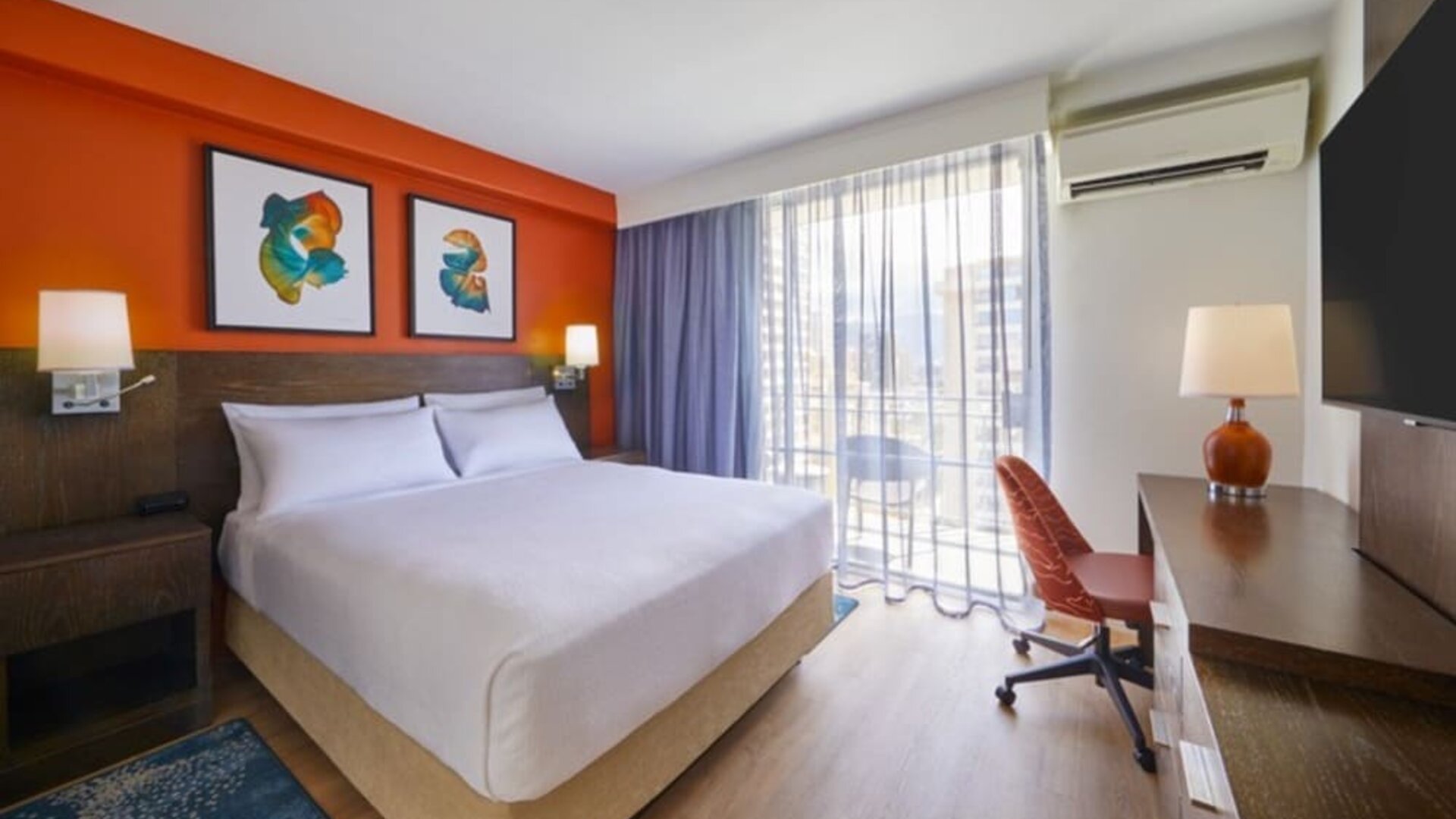 Bright king guest room with workspace and balcony access at Courtyard Waikiki Beach.