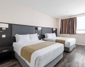 Double queen guest room with modern furnishings and natural light at Hotel Montreal Metropolitan, An Ascend Collection Hotel.
