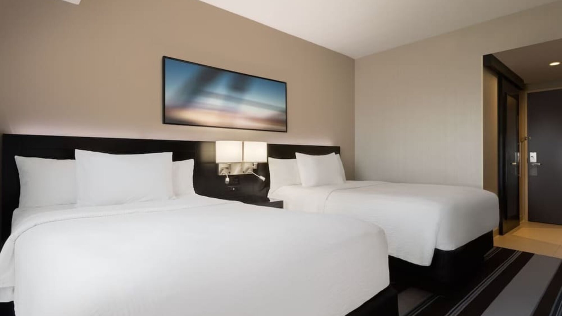 Guest room with two double beds and modern furnishings at Courtyard By Marriott New York JFK Airport.