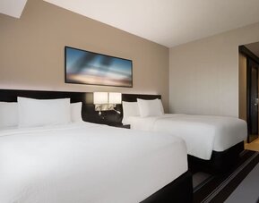 Guest room with two double beds and modern furnishings at Courtyard By Marriott New York JFK Airport.