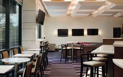 Contemporary dining and lounge area with seating and entertainment screens at Courtyard By Marriott New York JFK Airport.