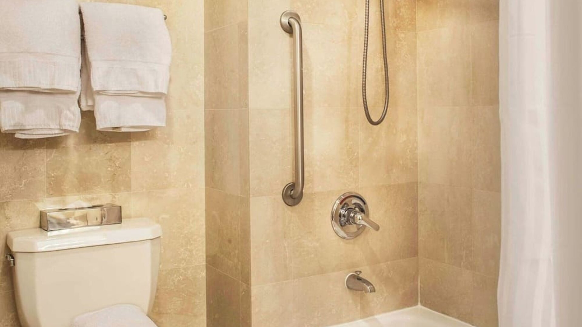 Accessible bathroom with bathtub, grab bars, and modern fixtures at Courtyard By Marriott New York JFK Airport.