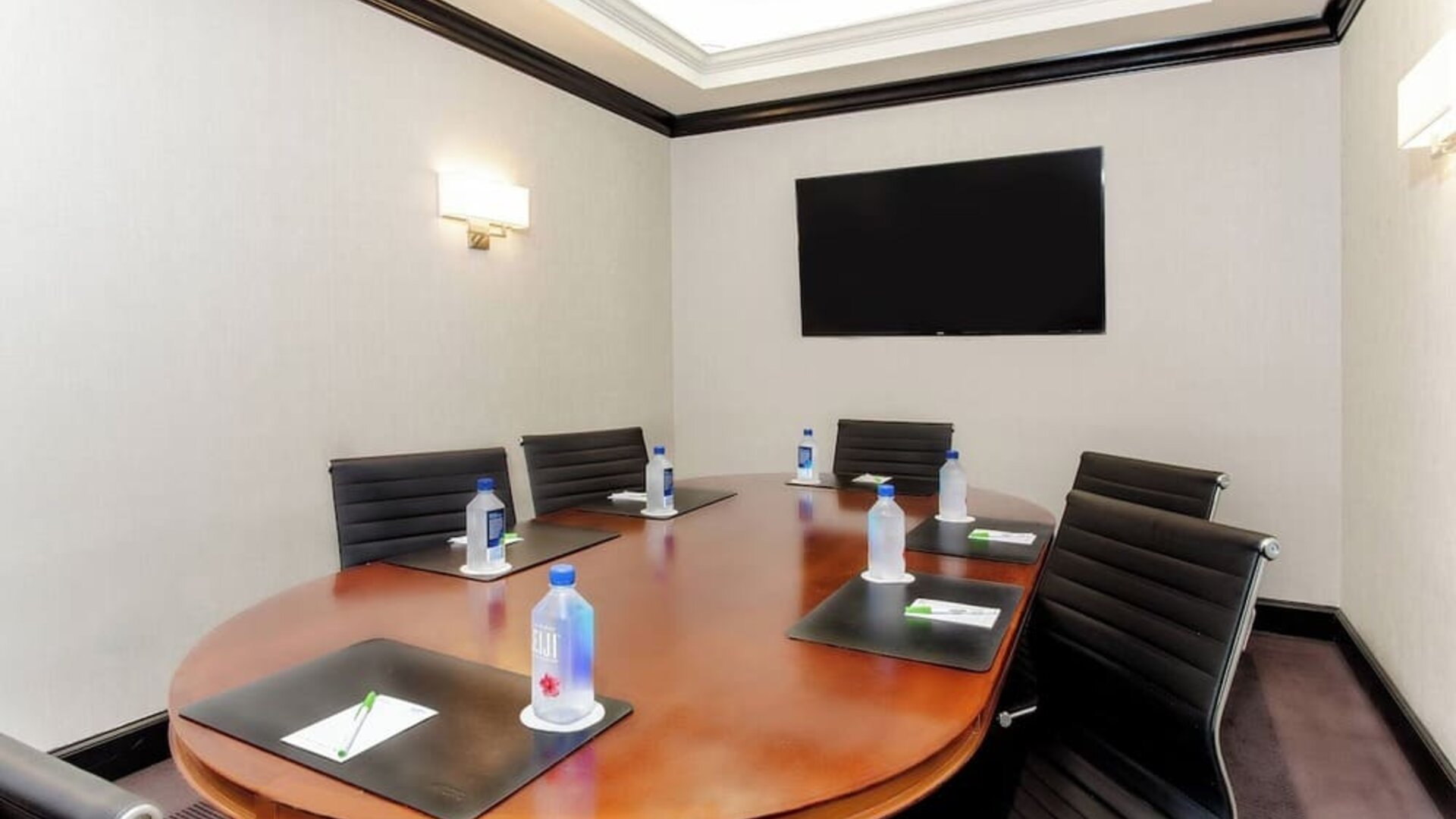 Private meeting room with conference table and presentation screen at Courtyard By Marriott New York JFK Airport.