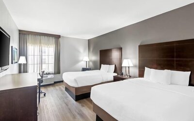 Spacious guest room with two beds, workspace, and large windows at La Quinta Inn & Suites By Wyndham Houston Energy Corridor.