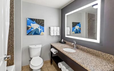 Modern bathroom with illuminated mirror and granite vanity at La Quinta Inn & Suites By Wyndham Houston Energy Corridor.
