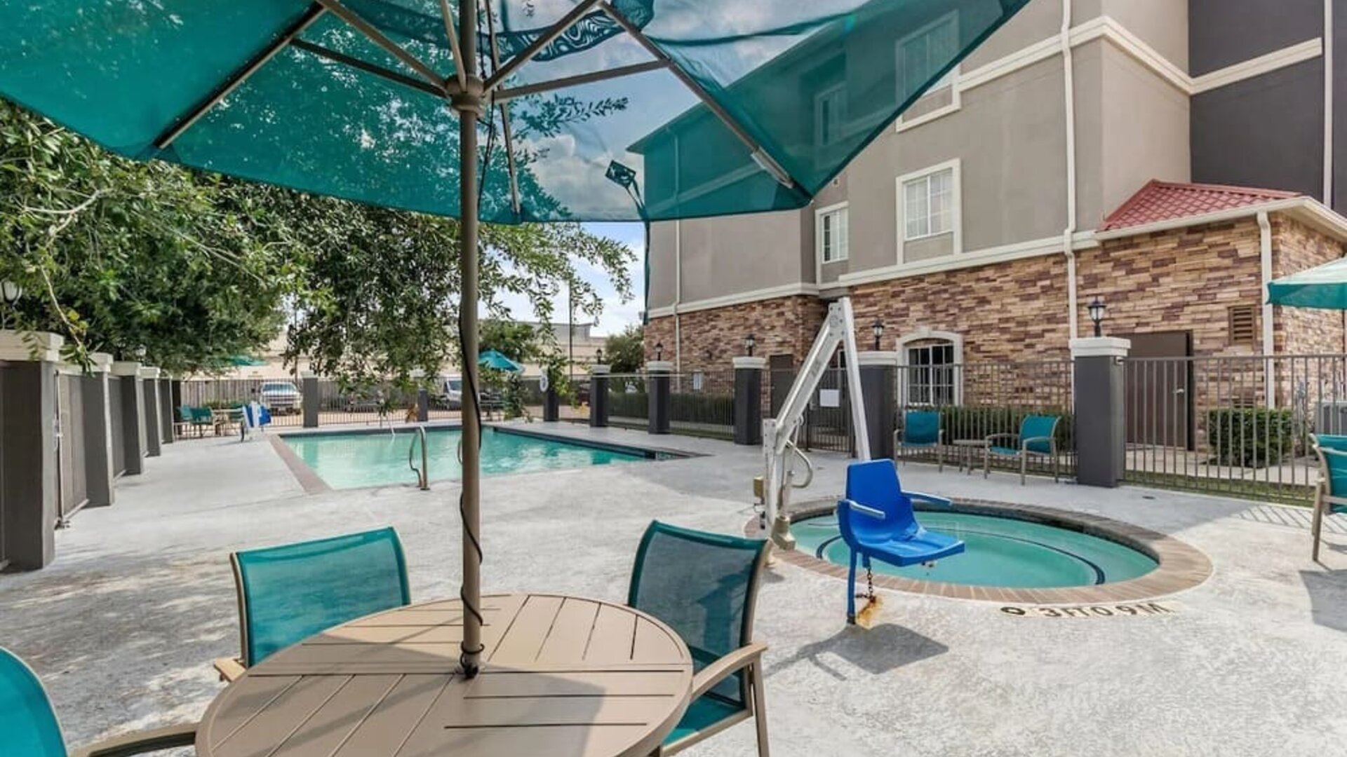 Outdoor swimming pool with accessible pool lift and shaded seating at La Quinta Inn & Suites By Wyndham Houston Energy Corridor.