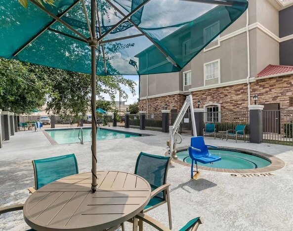 Outdoor swimming pool with accessible pool lift and shaded seating at La Quinta Inn & Suites By Wyndham Houston Energy Corridor.