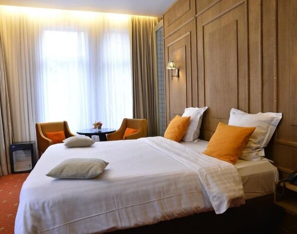 Spacious guest room with warm lighting, seating area, and contemporary furnishings at Hôtel Espérance.
