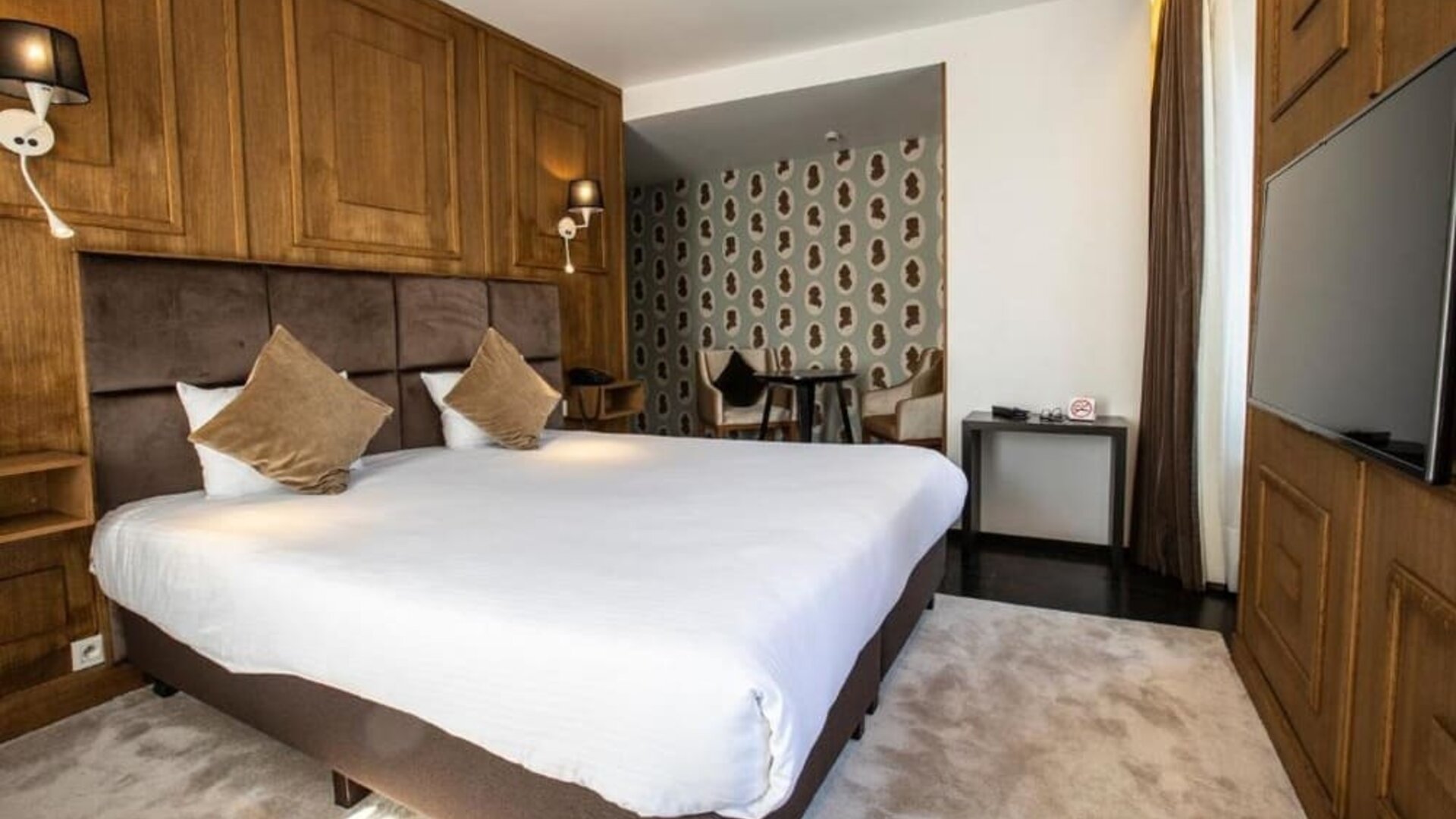 Spacious guest room with king bed, seating area, and television at Hôtel Espérance.