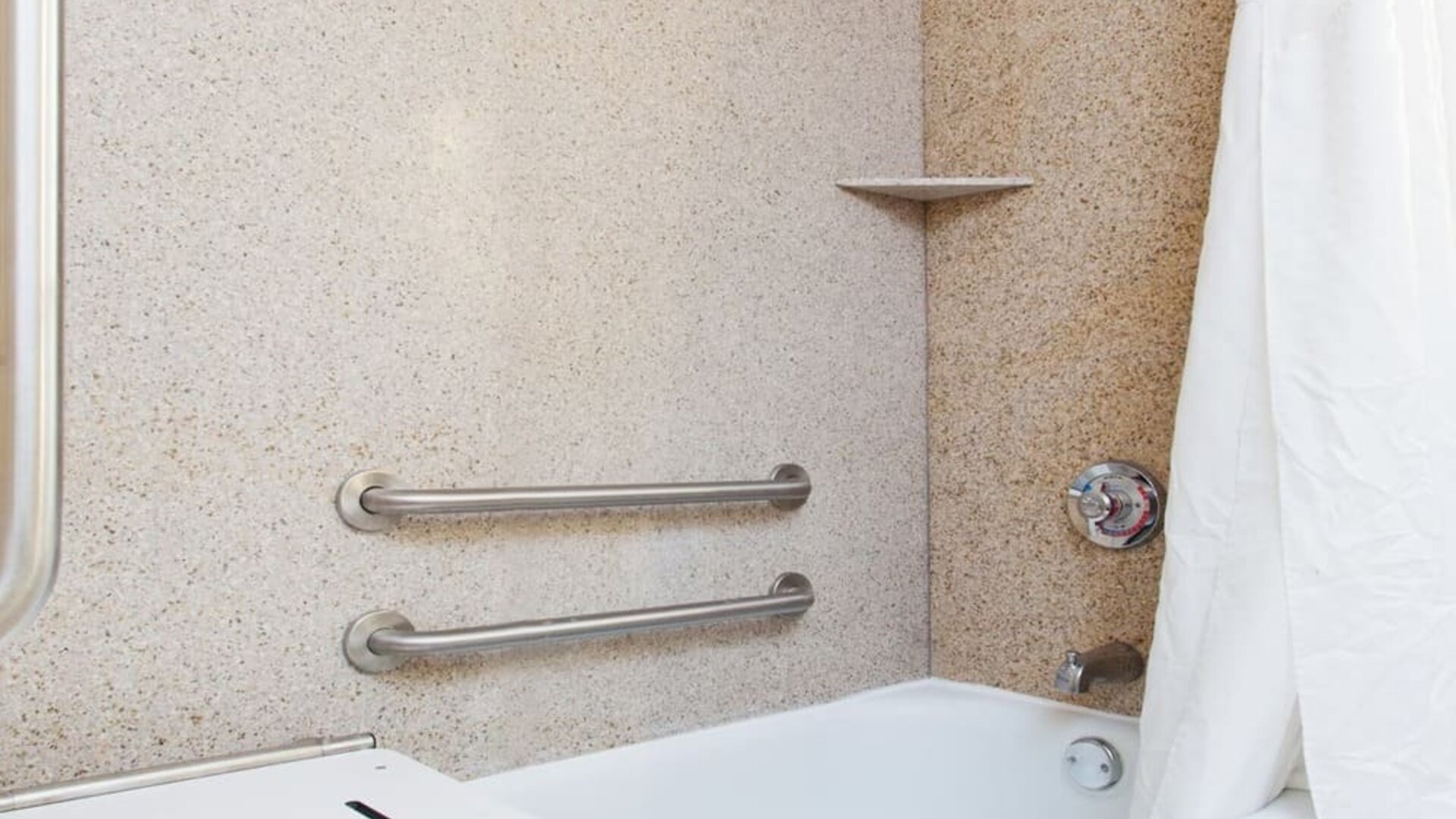Accessible bathroom with bathtub, safety grab bars, and transfer bench at Holiday Inn Downtown Shreveport.