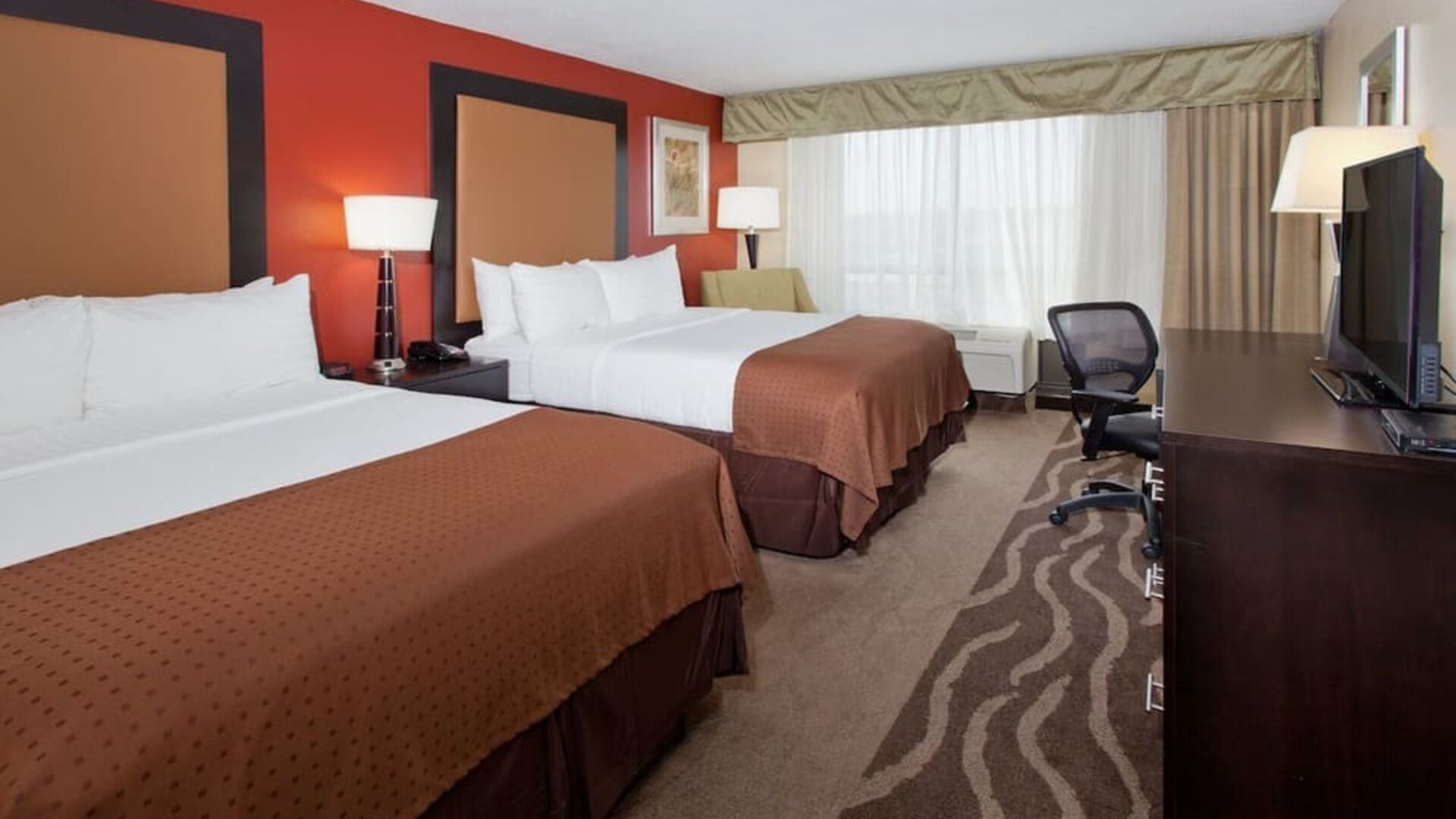 Large guest suite with two beds, sofa seating, and open floor plan at Holiday Inn Downtown Shreveport.