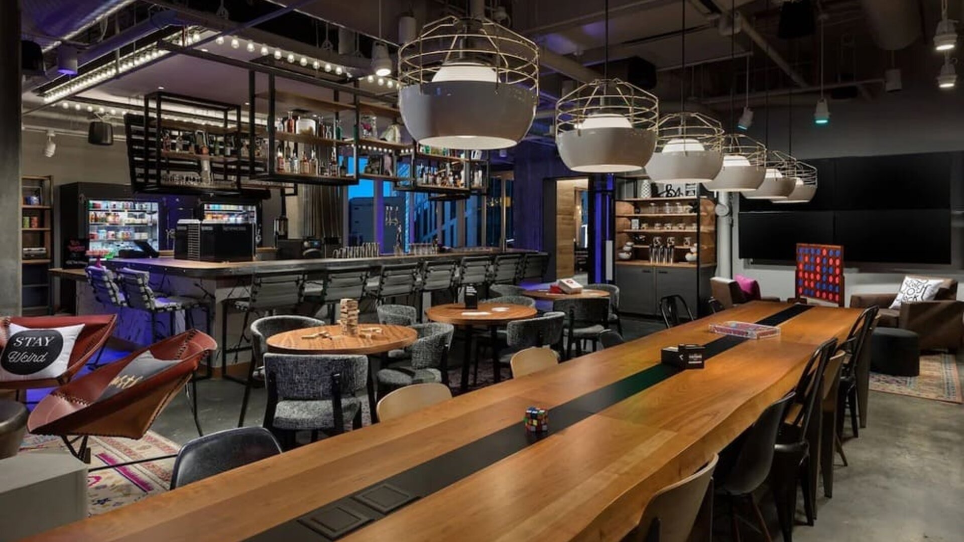 Stylish dining and lounge area with communal tables and pendant lighting at Moxy Boston Downtown.