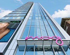 Glass high-rise hotel exterior with bright pink Moxy signage at Moxy Boston Downtown.