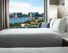 Bed positioned beside large window with harbor and city skyline view at Hilton Boston Logan Airport.
