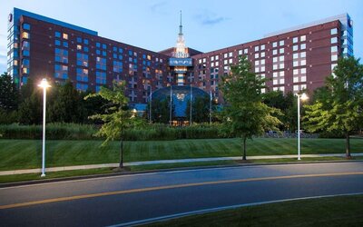 Evening exterior view of Hilton Boston Logan Airport surrounded by landscaped grounds and roadway lighting.