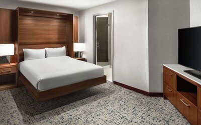 Guest room with platform bed, wood headboard, carpeted floor, and large TV at Hilton Boston Logan Airport.