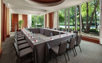 Meeting room with U-shaped conference setup, large windows, and garden views at Hilton Boston Logan Airport.