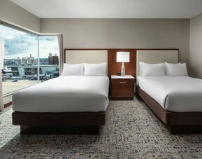 Guest room with two beds and large corner windows overlooking airport and city views at Hilton Boston Logan Airport.