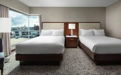 Guest room with two beds and large corner windows overlooking airport and city views at Hilton Boston Logan Airport.