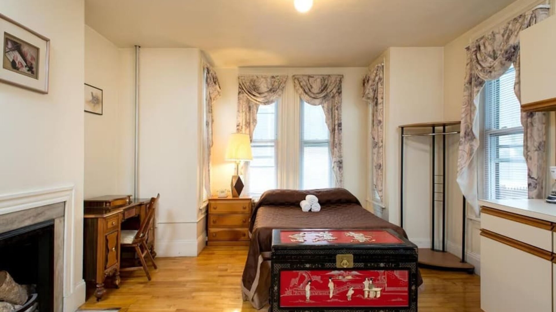 Spacious guest room with double bed, wooden desk, decorative chest, and hardwood floors at The Farrington Inn.