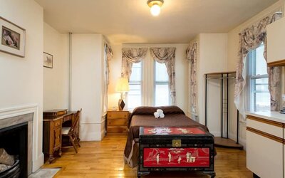 Spacious guest room with double bed, wooden desk, decorative chest, and hardwood floors at The Farrington Inn.