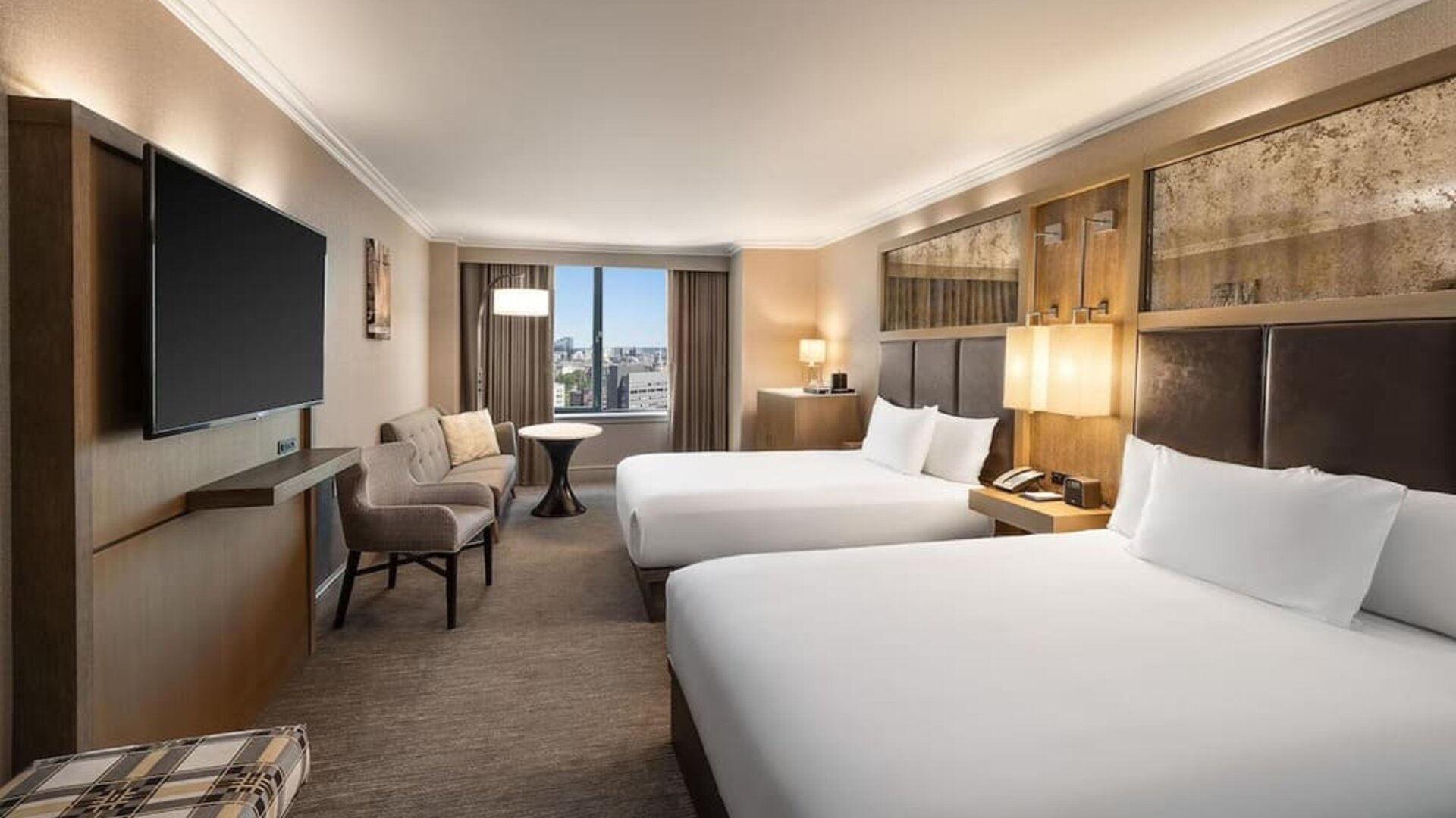 Spacious double queen guest room with city views, seating area, and large flat-screen TV at Hyatt Regency Boston.