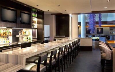 Contemporary hotel bar with marble countertops, high seating, and ambient lighting at Hyatt Regency Boston.