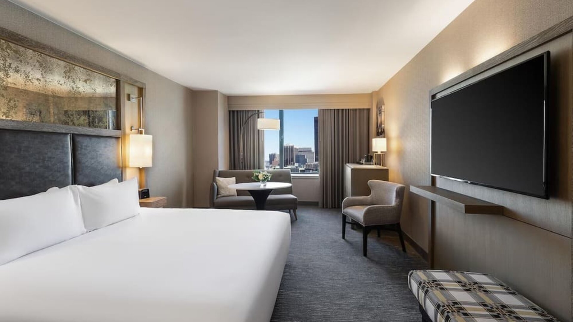 Contemporary king guest room with floor-to-ceiling windows, lounge seating, and city views at Hyatt Regency Boston.