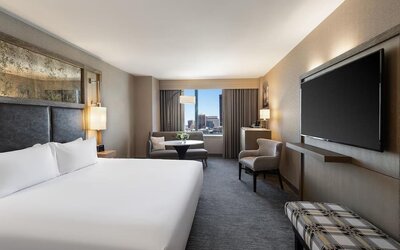 Contemporary king guest room with floor-to-ceiling windows, lounge seating, and city views at Hyatt Regency Boston.