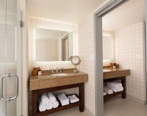 Contemporary bathroom vanity area with illuminated mirror, granite countertop, and glass walk-in shower at Hyatt Regency Boston/Cambridge.