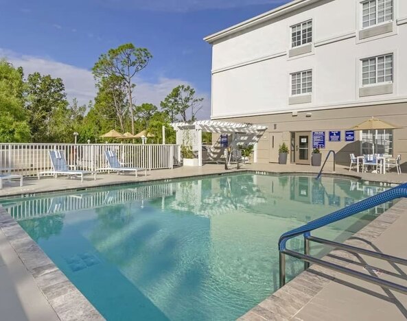 Outdoor swimming pool area with lounge chairs and shaded seating at Comfort Inn & Suites Port Charlotte-Punta Gorda.