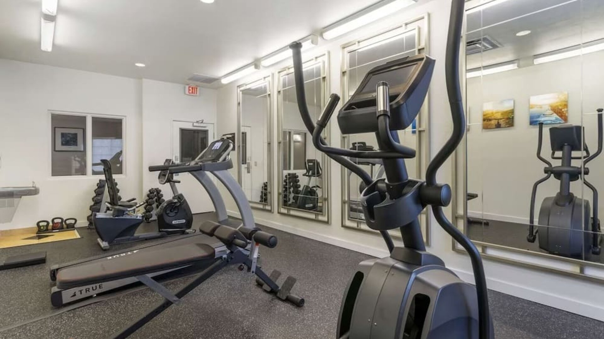 Well-equipped hotel gym with elliptical machines, treadmill, free weights, and mirrored workout space at Comfort Inn & Suites Port Charlotte-Punta Gorda.