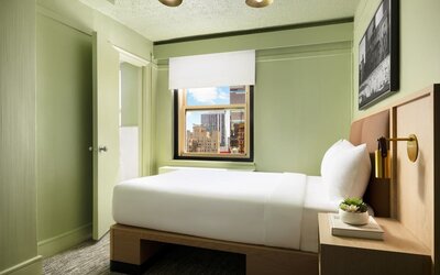 Cozy guest room with natural light, city views, and minimalist modern furnishings at Row NYC.