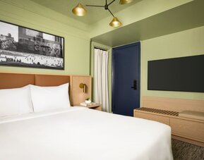 Contemporary guest room with minimalist furnishings, wall-mounted television, and modern city-inspired décor at Row NYC.