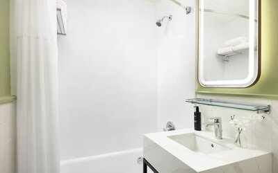Bright guest bathroom with clean white finishes, modern vanity, and walk-in shower at Row NYC.