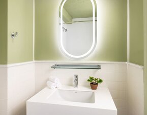 Compact modern bathroom with illuminated mirror, sleek vanity, and contemporary finishes at Row NYC.